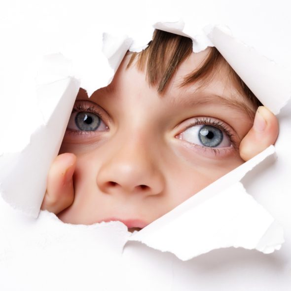 CHILDS FACE LOOKING THROUGH PAPER